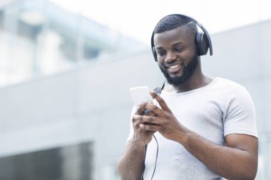 Afrikalı adam cep telefonu yla mesajlaşma ve müzik dinleme