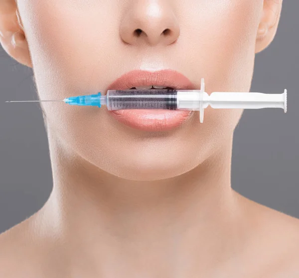Young woman with syringe in her mouth close up — Stock Photo, Image