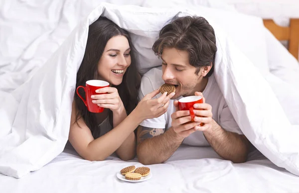 Feliz casal milenar desfrutando de biscoitos e café — Fotografia de Stock