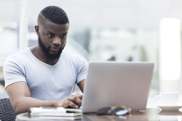 Συγκεντρωμένη νέος Αφρικανός Αμερικανός τύπος που εργάζεται σε φορητό υπολογιστή — Φωτογραφία Αρχείου