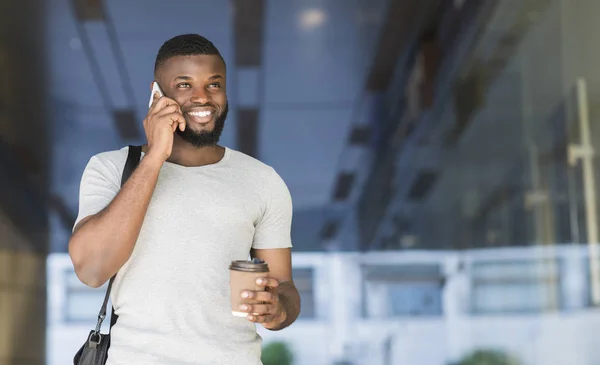 Empresário africano sorridente caminhando com café para ir — Fotografia de Stock