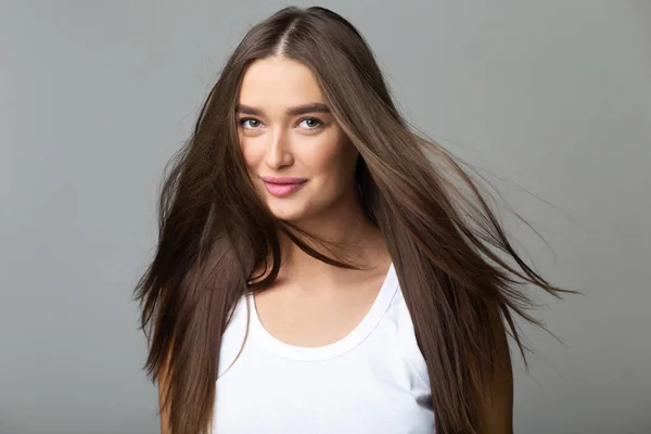 Chica joven con el pelo largo volando, fondo gris — Foto de Stock