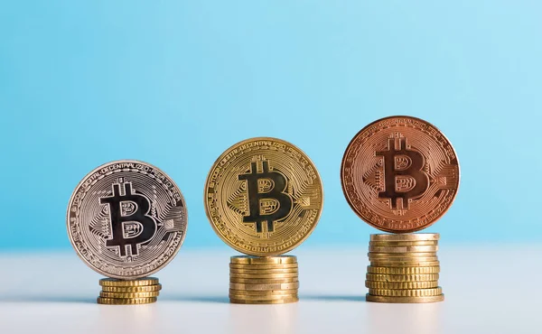 Mavi arka planda farklı derecelendirmeye sahip Bitcoin paraları