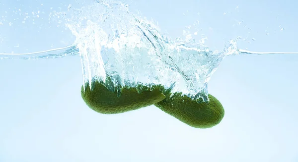 Paar frische Avocados fallen ins klare Wasser — Stockfoto