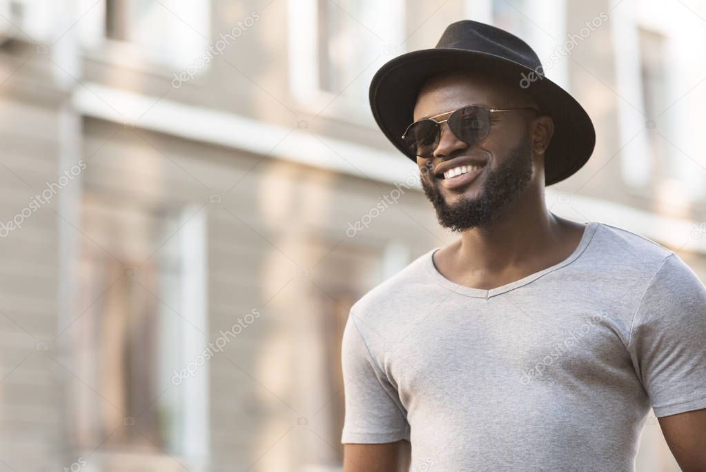 African man in hat walking near the old buildings in the city