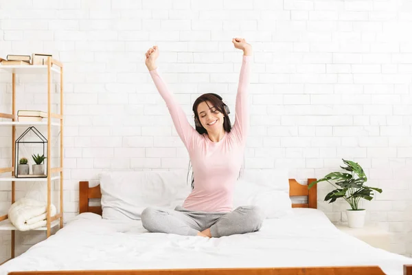 Energetic young woman singing and dancing in bed Stock Photo