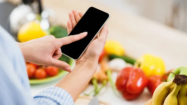 Search recipe. Woman using smartphone, cooking food