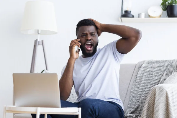 Jeune homme déçu travaillant sur un ordinateur portable avec les mains sur la tête — Photo