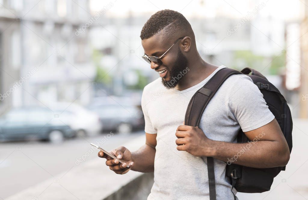 Happy african guy chatting with friends on cellphone