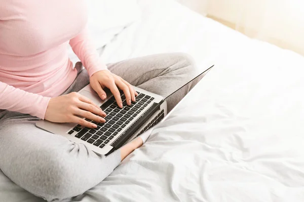 Woman journalist typing on laptop in bed