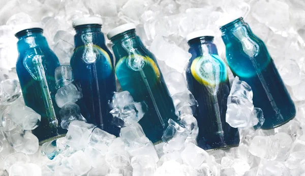 Fruchtblaues Entgiftungswasser in Glasflaschen zum Verkauf auf Eis — Stockfoto