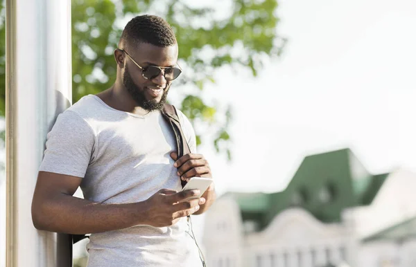 Jovem africano conversando no telefone enquanto espera ônibus — Fotografia de Stock