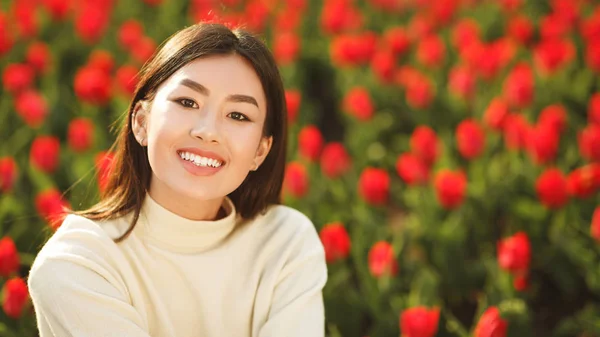 Feliz ásia menina no tulipas jardim sorrindo para câmera — Fotografia de Stock