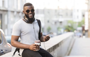Kahve ile Casual Afrikalı adam gitmek, cep telefonu ve kulaklık