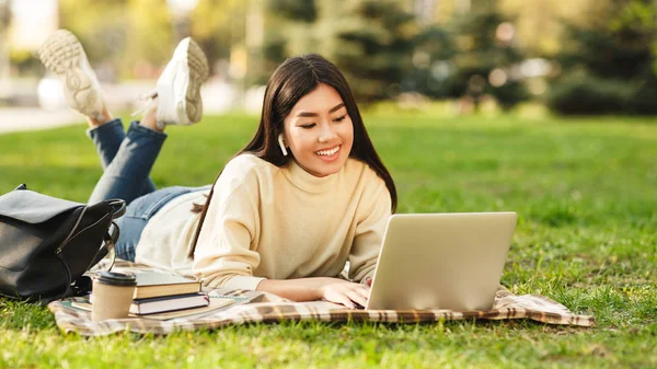 Счастливая студентка с ноутбуком готовится к экзаменам на открытом воздухе — стоковое фото