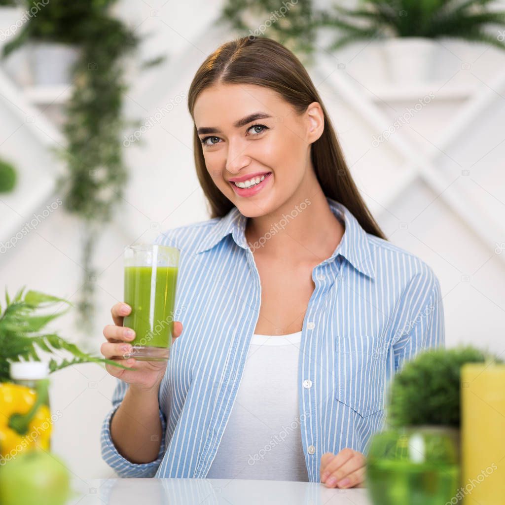 Happy woman holding glass of healthy smoothie