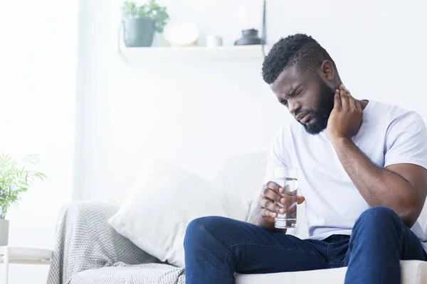 Hombre afroamericano que sufre de dolor de cuello en casa —  Fotos de Stock