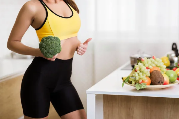 Gewicht verlies concept. Meisje houdt broccoli en toont duim omhoog — Stockfoto