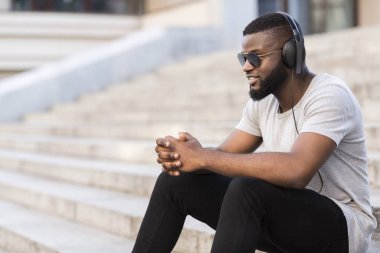 Sakin Afrikalı adam merdivenlerde oturan ve açık müzik dinlerken