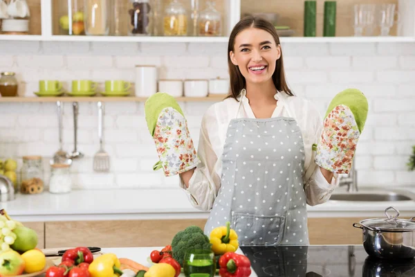 Glückliche Hausfrau mit Ofenhandschuhen und Schürze — Stockfoto