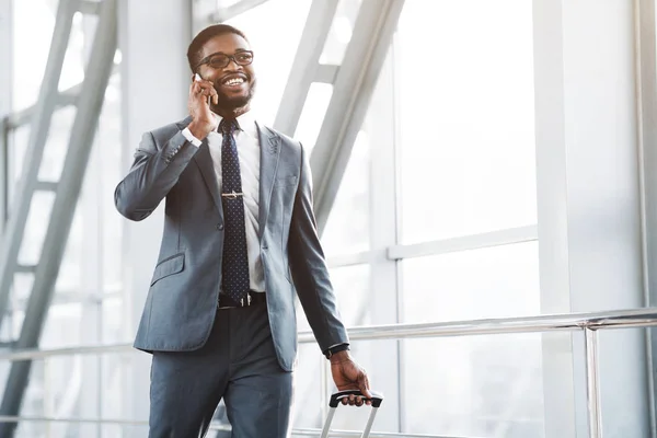 Empresario afro ocupado hablando por teléfono, llegando al aeropuerto — Foto de Stock