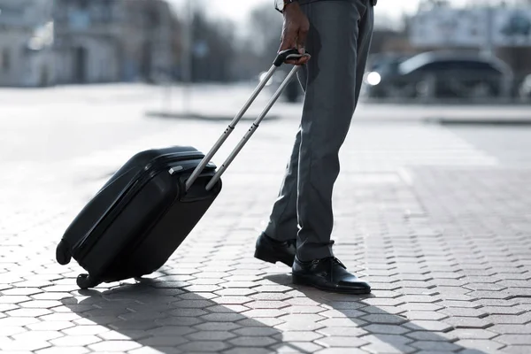 Бизнесмен гуляет с чемоданом на улице, прибывая в аэропорт — стоковое фото