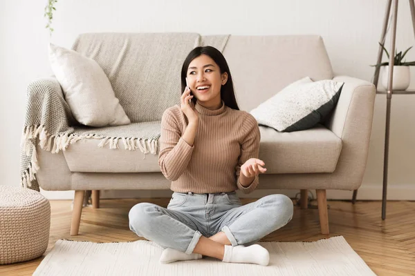 Ragazza adolescente che parla al telefono, seduta sul pavimento vicino al divano — Foto Stock