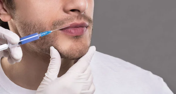 Médico insertando inyección de ácido hialurónico en los labios de los hombres — Foto de Stock