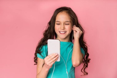 Mutlu kız öğrenci arka plan üzerinden akıllı telefon müzik dinleme