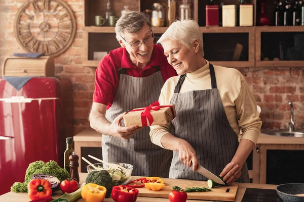 Bakım yaşlı adam mutfakta eşine hediye kutusu veren