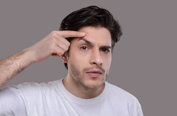 Grave bell'uomo guardando il suo viso, esaminando le rughe — Foto Stock