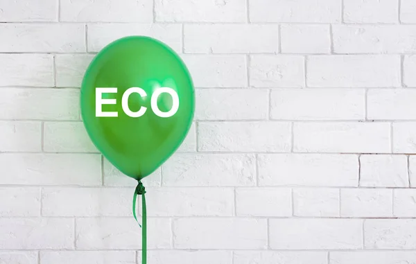 Eco Green helium ballong med vit text på tegelvägg — Stockfoto