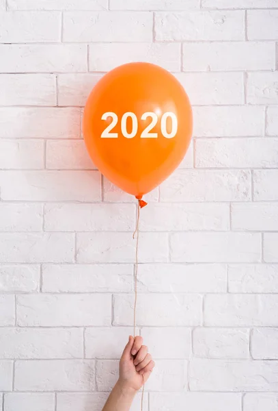 Orangefarbener Luftballon mit weißem Text in der Hand auf Ziegelsteinwand — Stockfoto