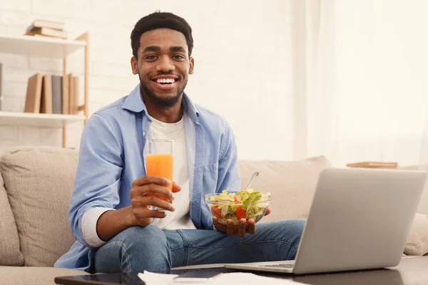 Cheerful african-american man eating healthy lunch at home