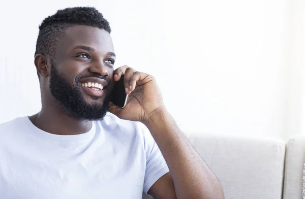 Joven hombre negro alegre hablando en el teléfono inteligente —  Fotos de Stock