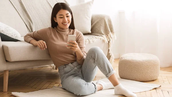 Lycklig tjej chattar i sociala nätverk på telefonen hemma — Stockfoto