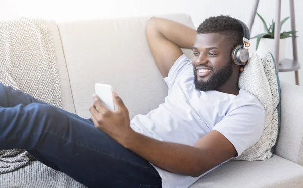 Schwarzer Mann mit Kopfhörer schaut Film auf Smartphone — Stockfoto