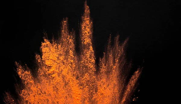 Abstract colored dust explosion of orange holi on black — Stock Photo, Image