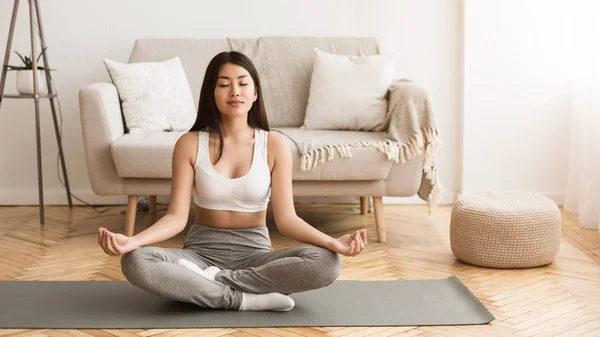 Menina asiática praticando Yoga na posição de lótus em casa — Fotografia de Stock