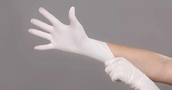 Doctor poniéndose guantes estériles en gris — Foto de Stock