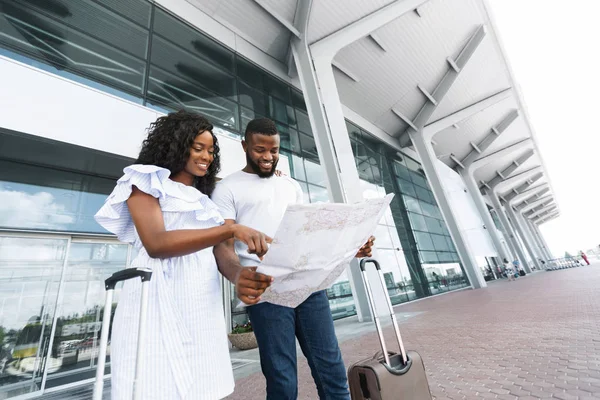 Joven pareja afroamericana mirando el mapa en el edificio del aeropuerto — Foto de Stock