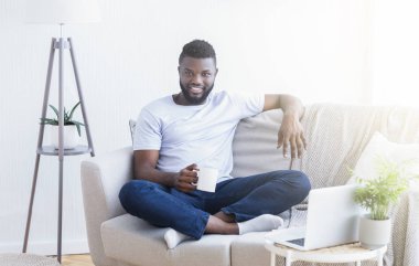 Neşeli Afrikalı adam ev ofisinde dinlenme zevk
