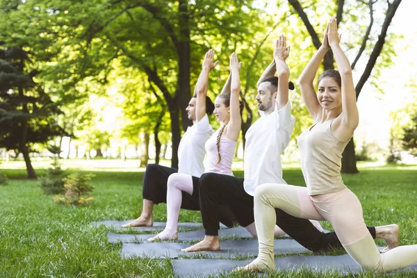 Grupo de personas haciendo yoga en guerrero posan al aire libre — Foto de Stock