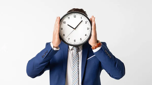 Homem escondendo seu rosto atrás do relógio no fundo branco — Fotografia de Stock