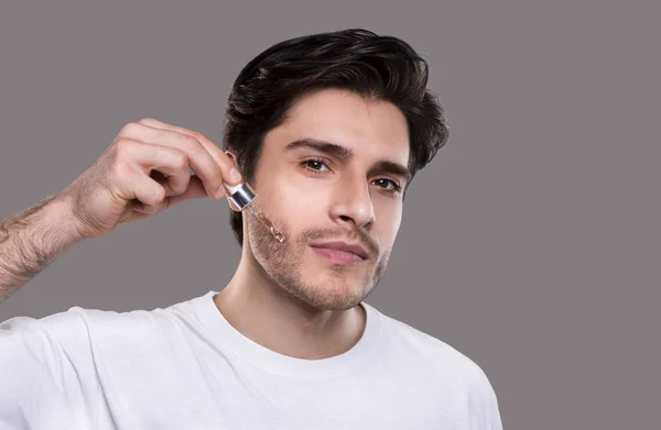 Młody mężczyzna stosujące organiczne serum na twarz — Zdjęcie stockowe