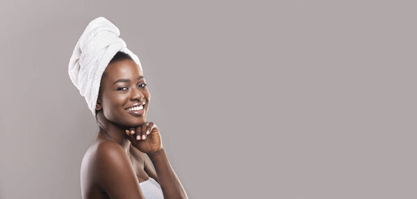 Positive african american woman enjoying spa procedures, grey panorama background with empty space
