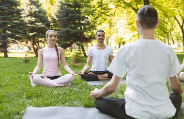 Yoga öğretmeni ve açık sınıfta yeni başlayanlar, kolay duruşlar yapma