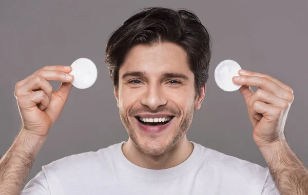 Hombre alegre sosteniendo almohadillas de algodón para la limpieza de la cara — Foto de Stock