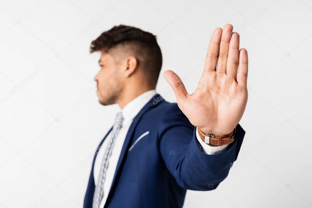 Young hispanic man doing stop gesture on white background