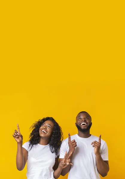 Happy african-american man and woman pointing fingers upwards — Stock Photo, Image